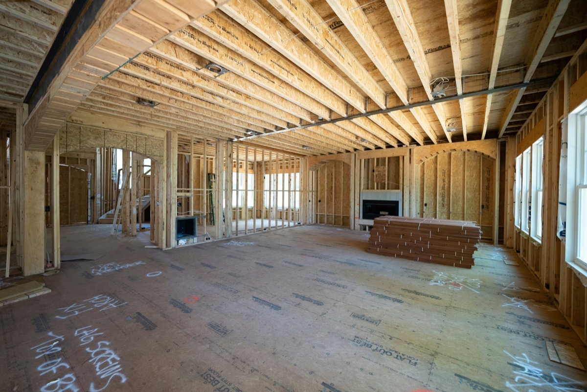 Framed interior of a home under construction with fresh lumber and flooring staged